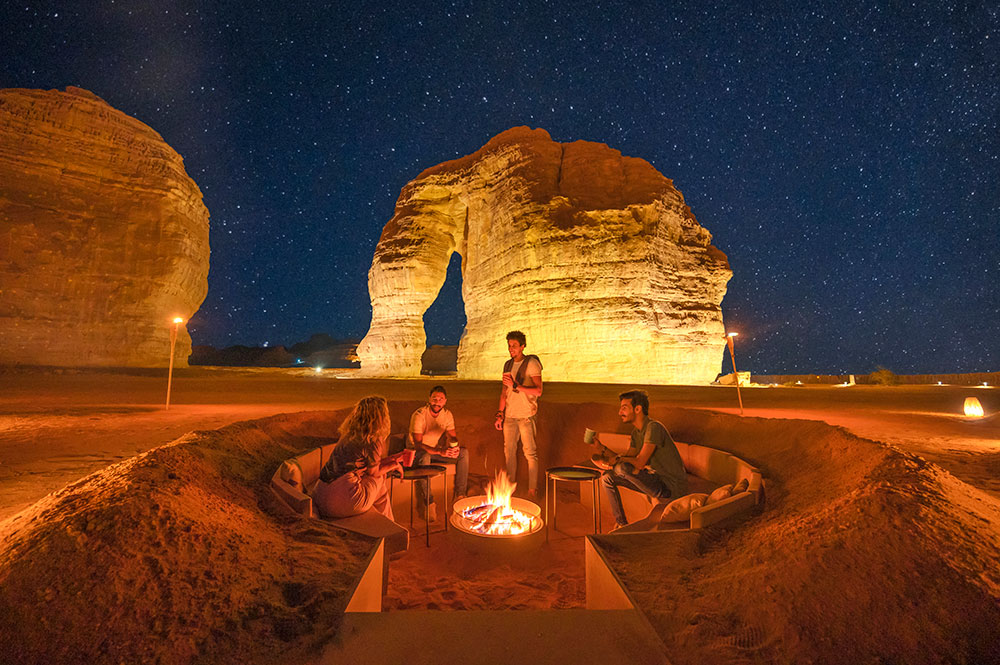 Menschen grillen nachts vor der Elefantenstatue in AlUla.
